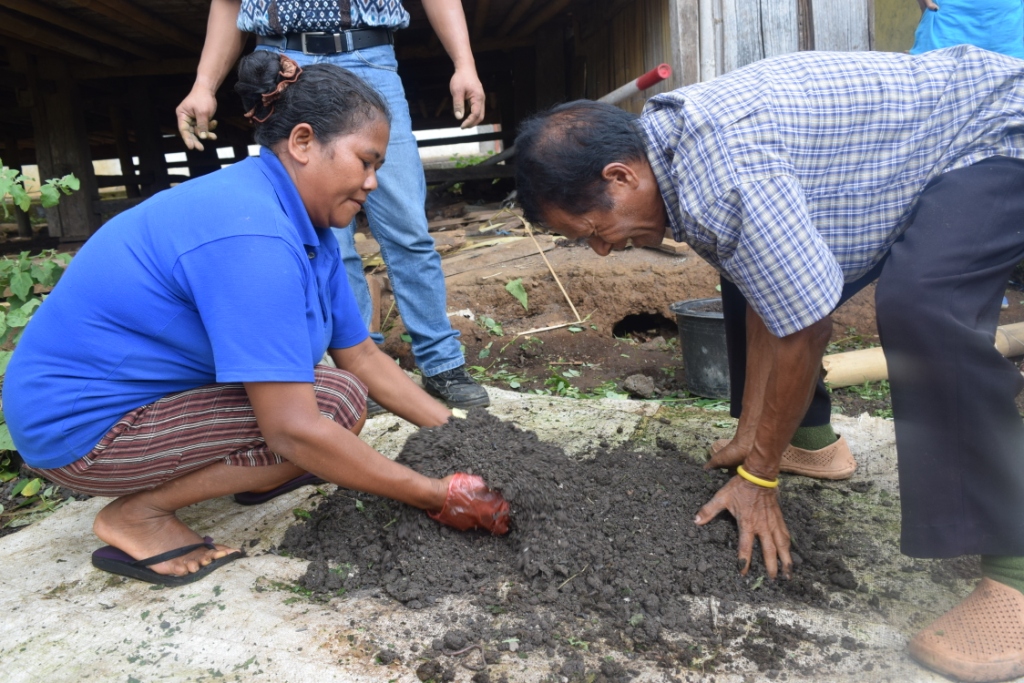 Bapak Jony (right) demonstrating how to compose organic fertilizer during a home garden training in Enabhara Subvillage