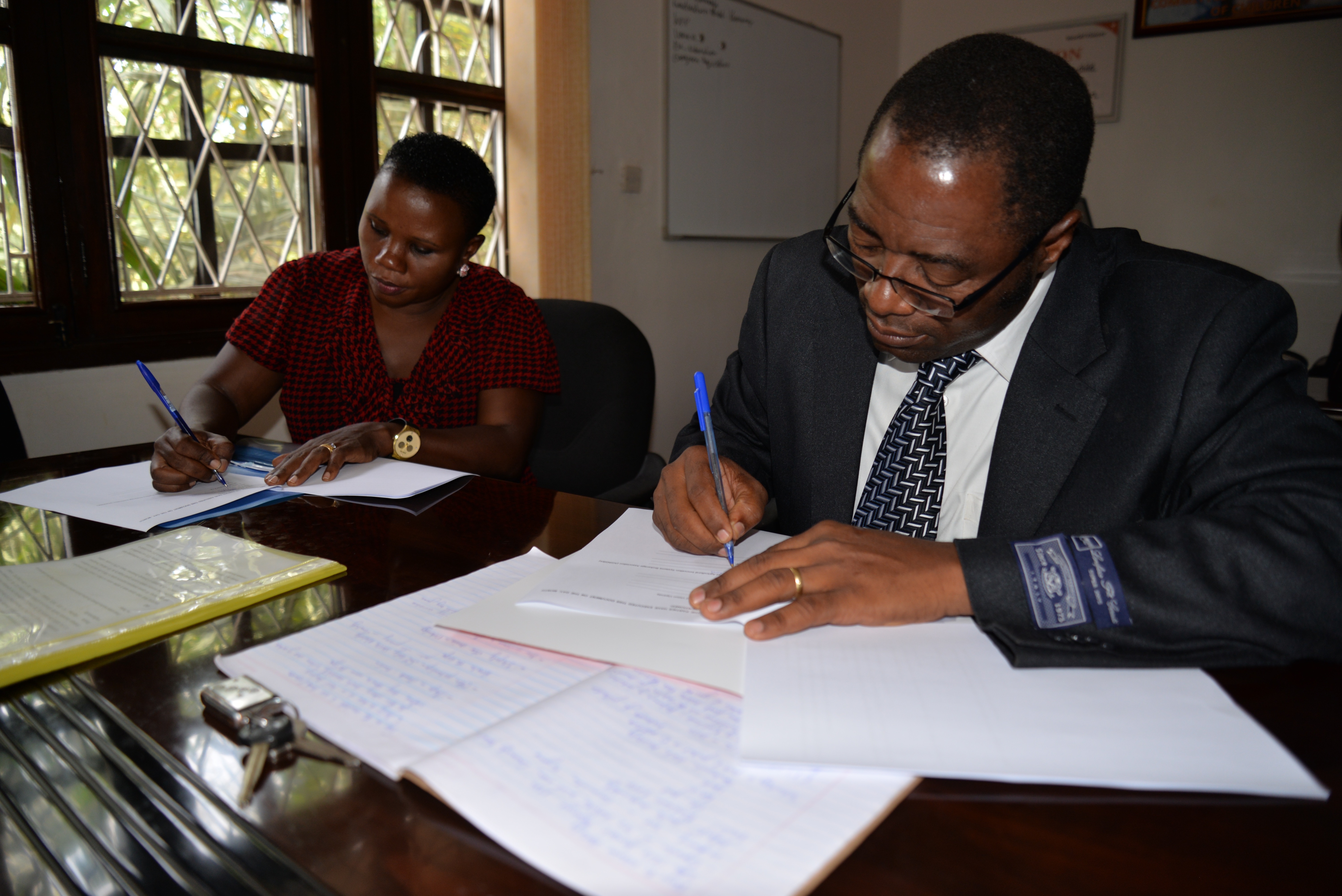 Tina Mukunda (Left), the World Vision Uganda senior programmes director joins Prof. Moses Tenywa, the Director of Agricultural innovations systems brokerage association to sign agreement documents.