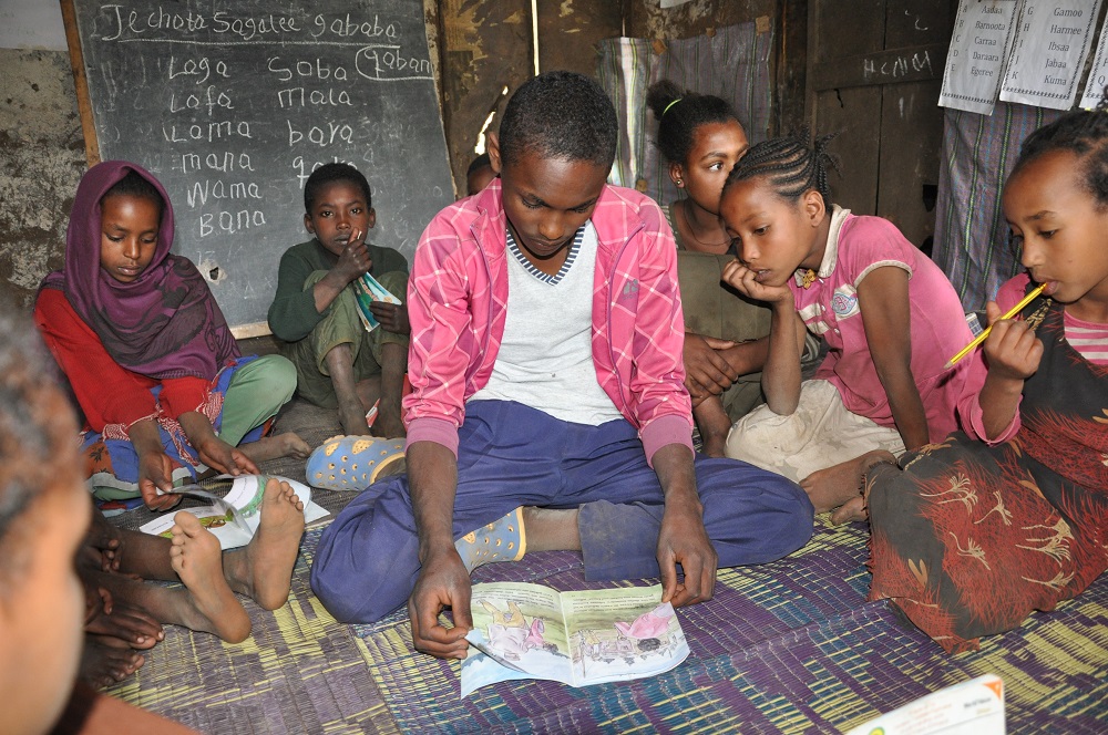 Giduma helps children in his local reading camp learn to read