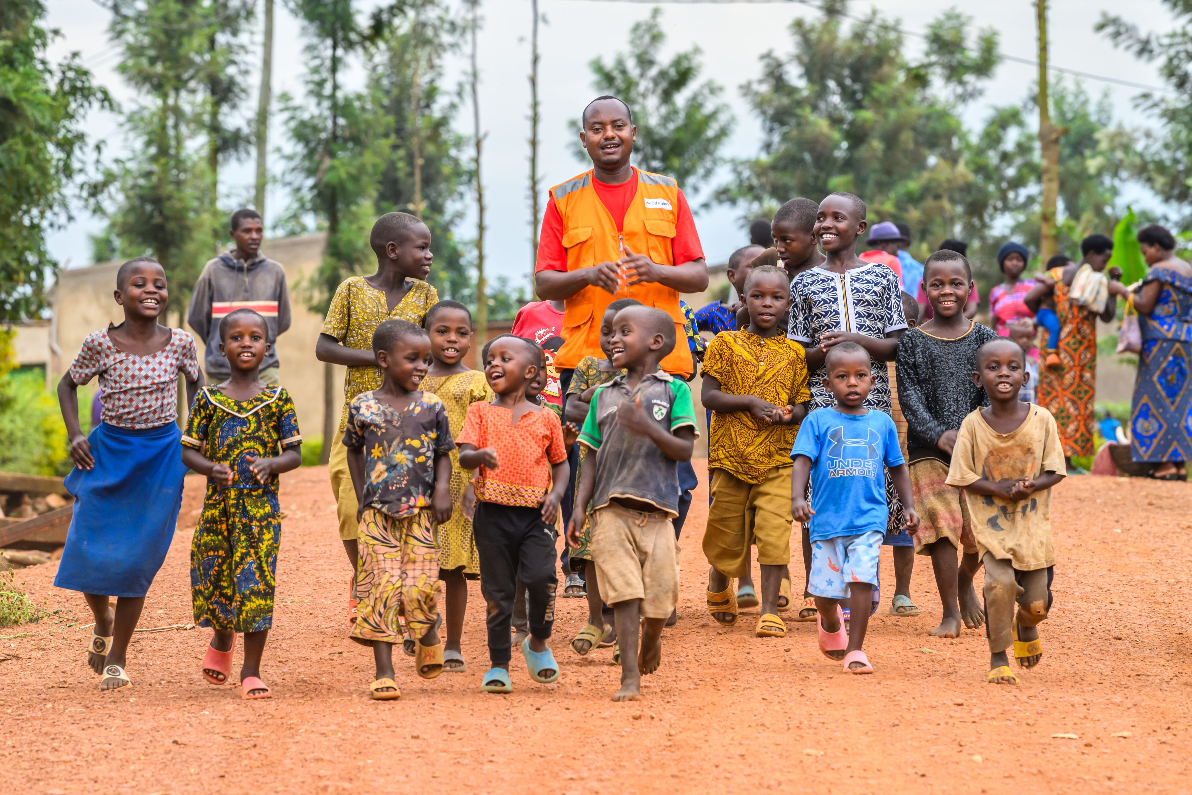 World Vision Staff walking with a group of happy children