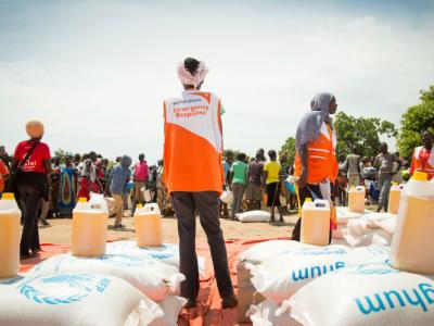 World Vision aid worker stands among bags of food aid
