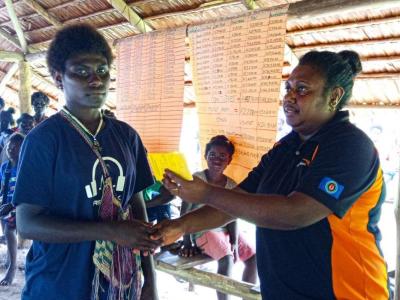 Azaneth, receiving her savings on the share-out ceremony by WVPNG Woven savings officer..jpg