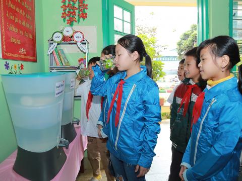 Children gather around clean water in their classroom