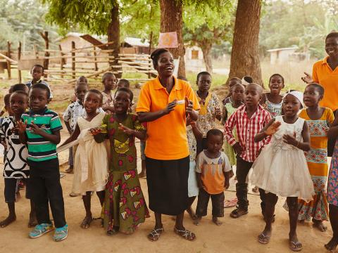 A World Vision employee sings with a group of children