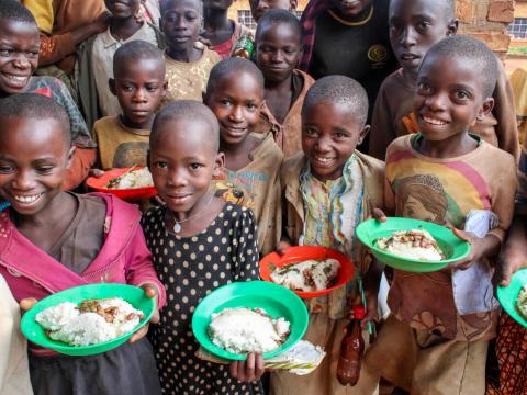 A group of school children hold meals at a canteen in Burundi