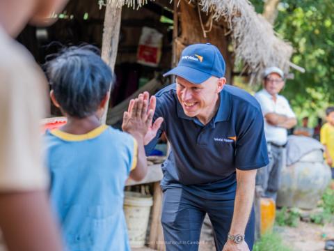 World Vision International President and CEO greets a boy in Cambodia with a high-five