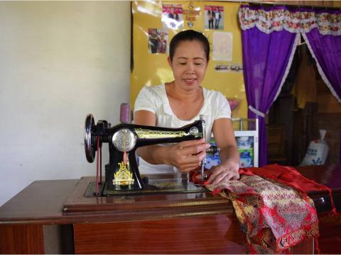 One of the "Mekar Basule", a sewing group members is sewing clothes ordered by the customer.