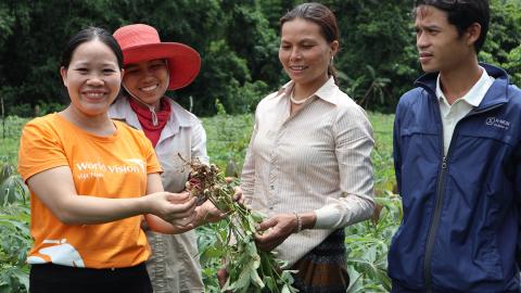 A World Vision Viet Nam employee works with farmers to increase crops. 