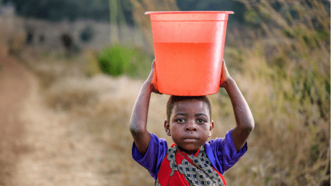Ireen holding a bucket of clean water on her head