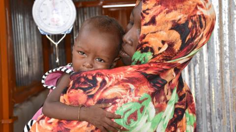 malnourished child on mother's shoulder