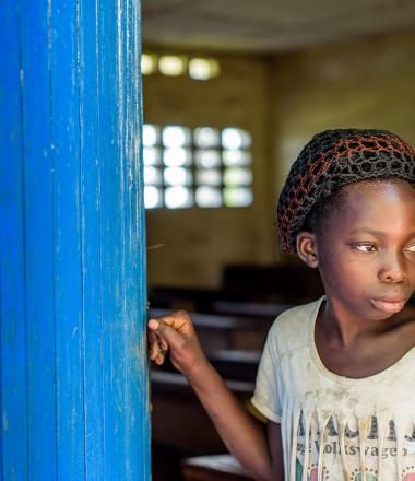 A young girl stands at her school in DRC