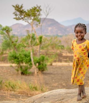 A girl in Malawi stands in a field