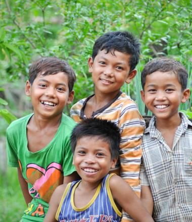 Four Khmer boys smiling at camera standing in garden