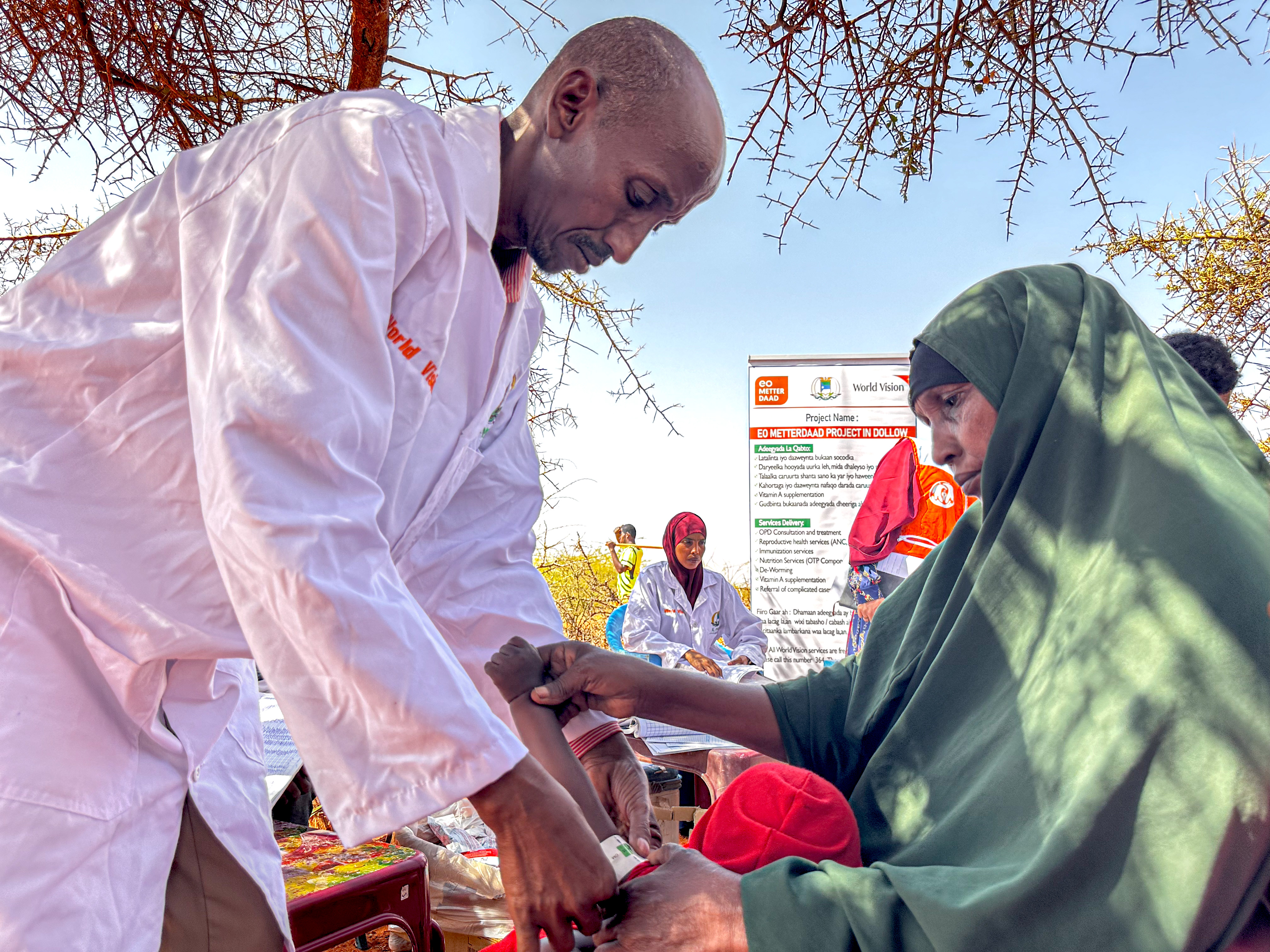 Dahabo, a participant in the EO Metterdaad project, with her grandchildren at a World Vision mobile clinic, receiving life-saving treatment for malnutrition through the program.