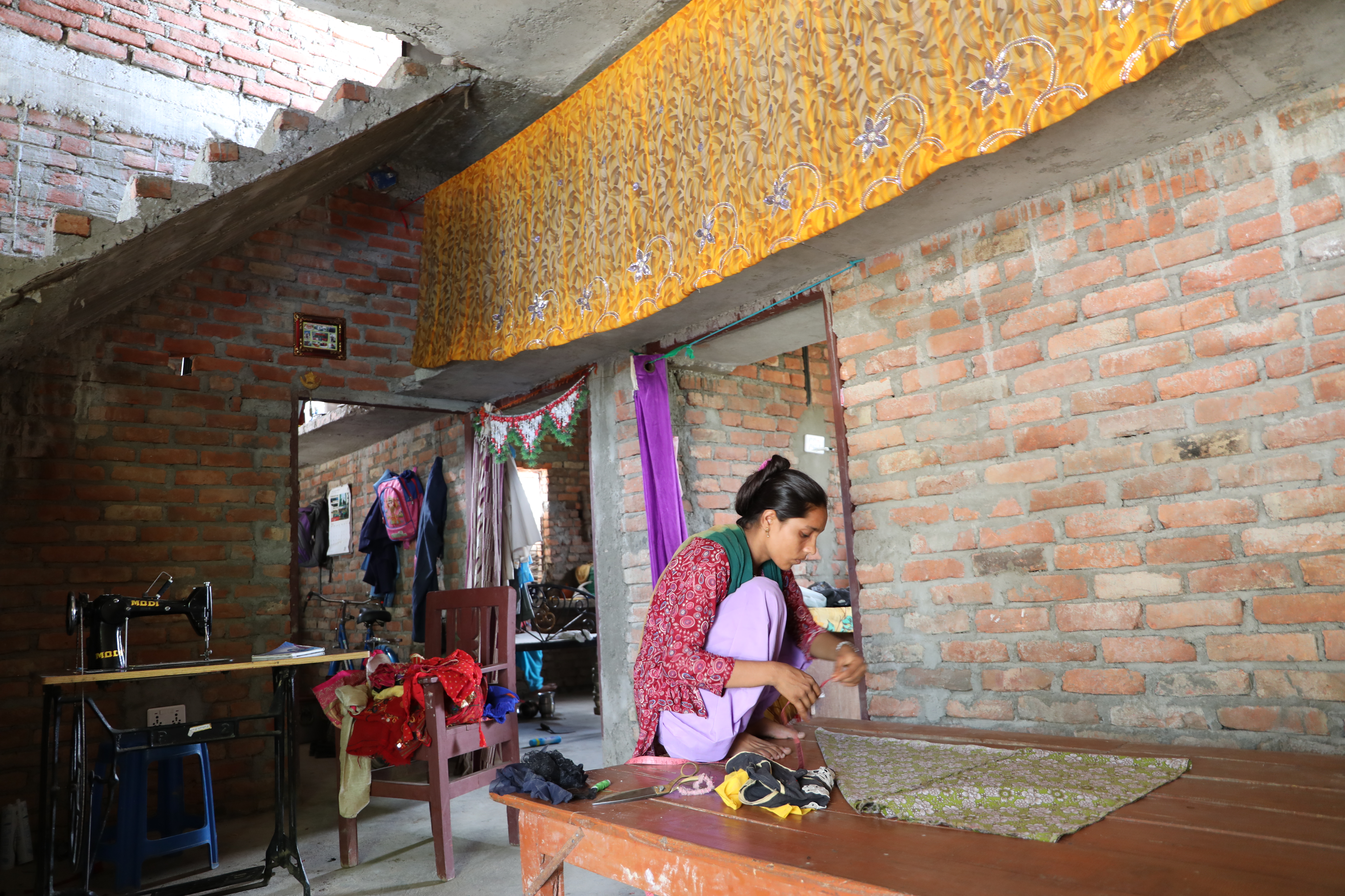 Noorjahan cuts a cloth piece to prepare a frock