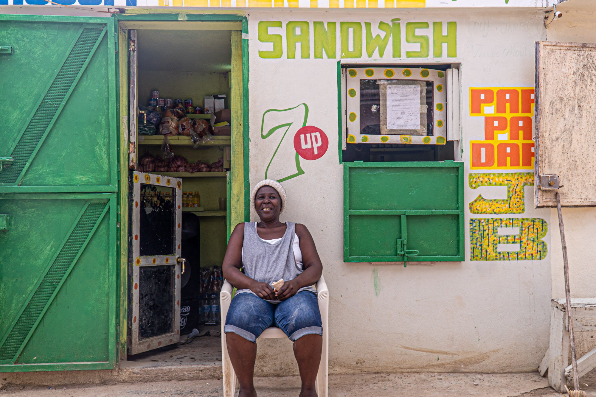 Milienne sits outside her small business in Haiti