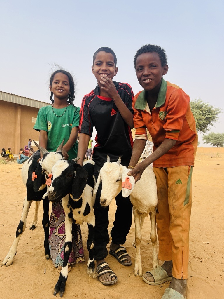 Smiling children with a goat.