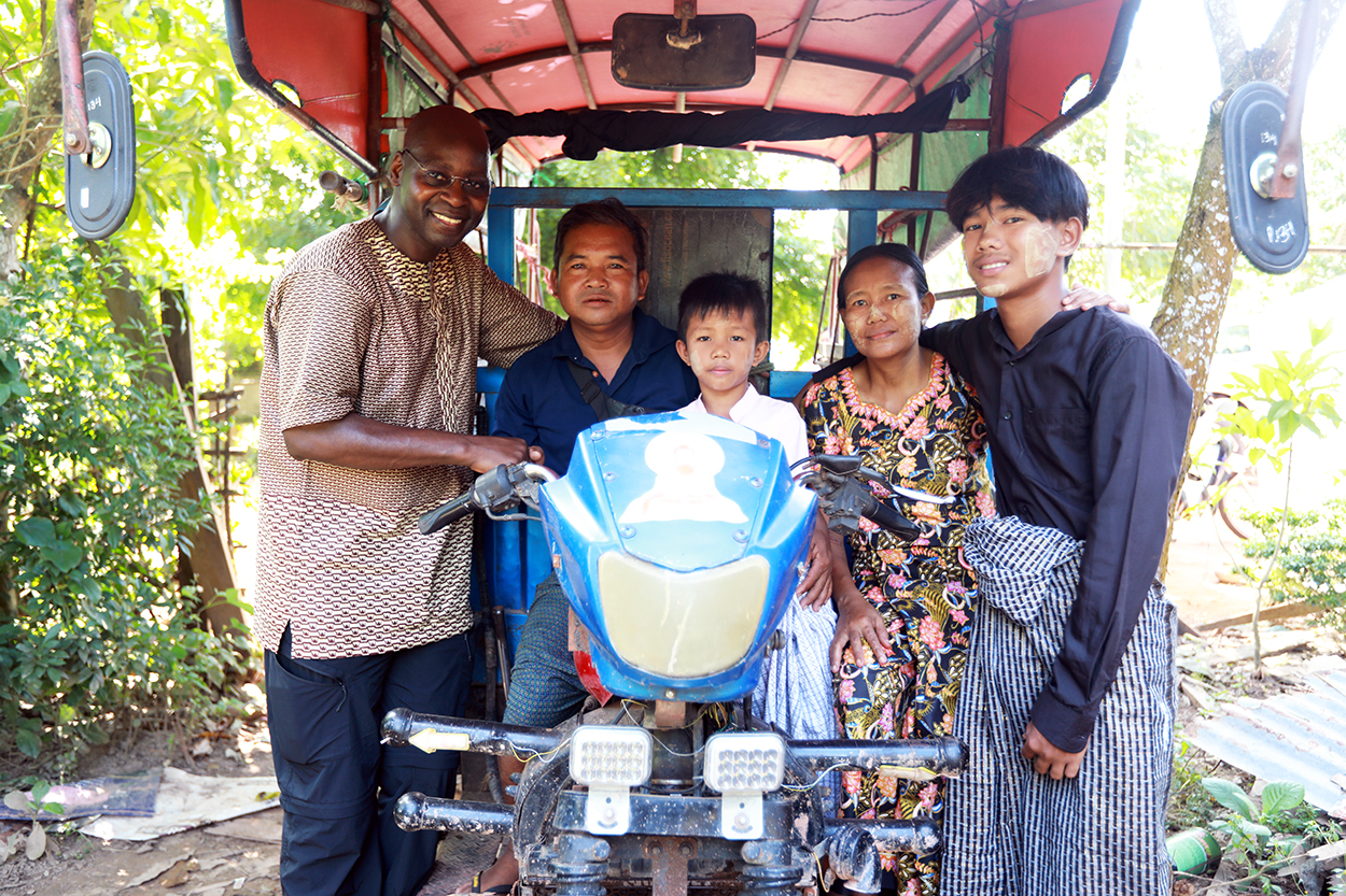 World Vision's Chief Field Officer with family in Myanmar on Trike they now rent thanks to World Vision's programmes