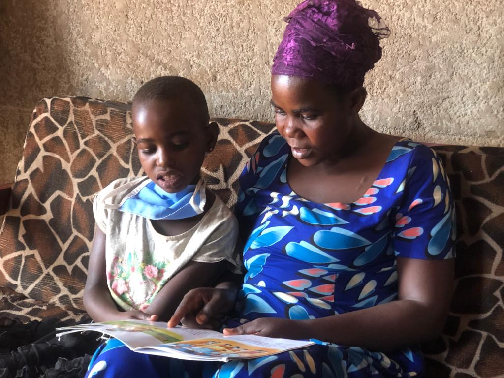 Kellen and her mother joyfully reading a story book they got from the reading camp