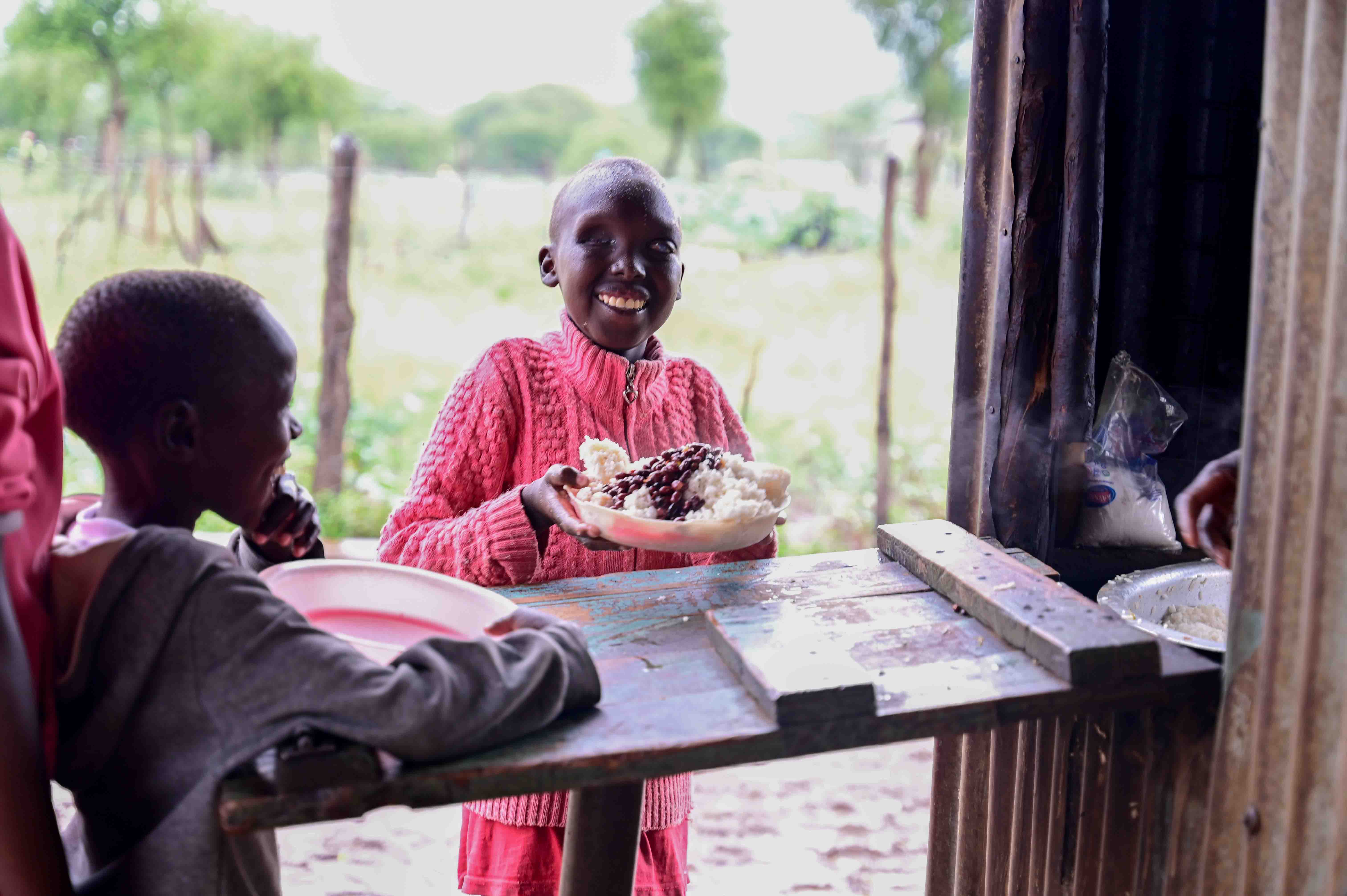 Students being served meals at lunch time. The students have planted legumes, vegetables and fruit trees in their farm. 