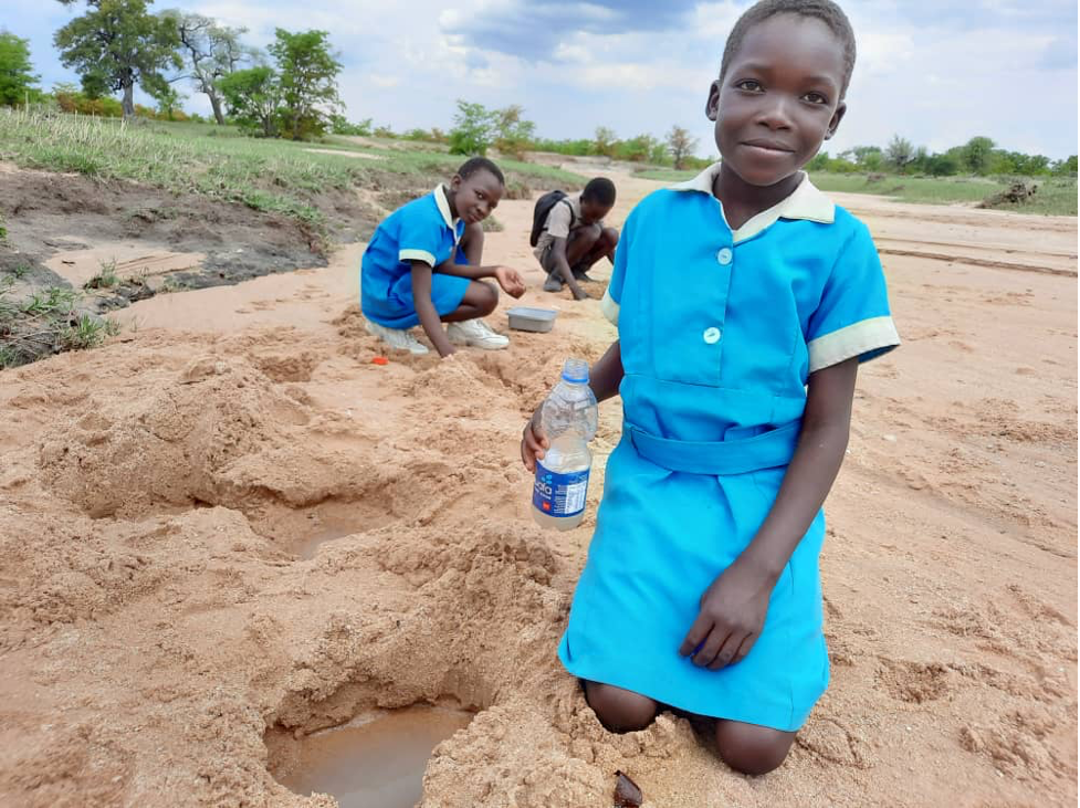 Langelihle Ndlovu gets water from a river bed before the construction of a piped water scheme at her school