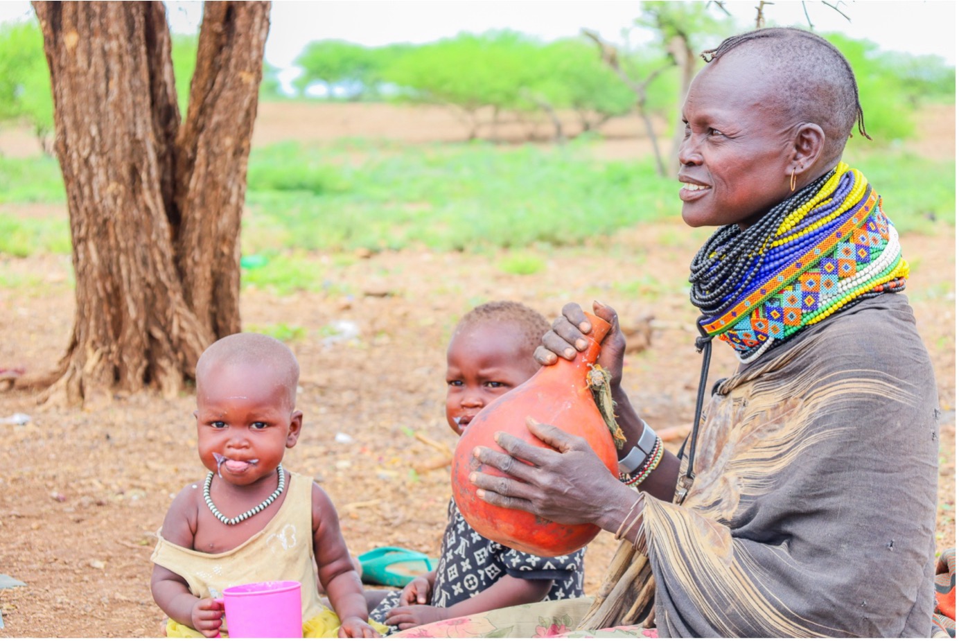 Akuam serves her children goat milk from the galla goats her family received through the support of World Vision through the K-DREAM Project. © World Vision Photo/Felix Pilipili