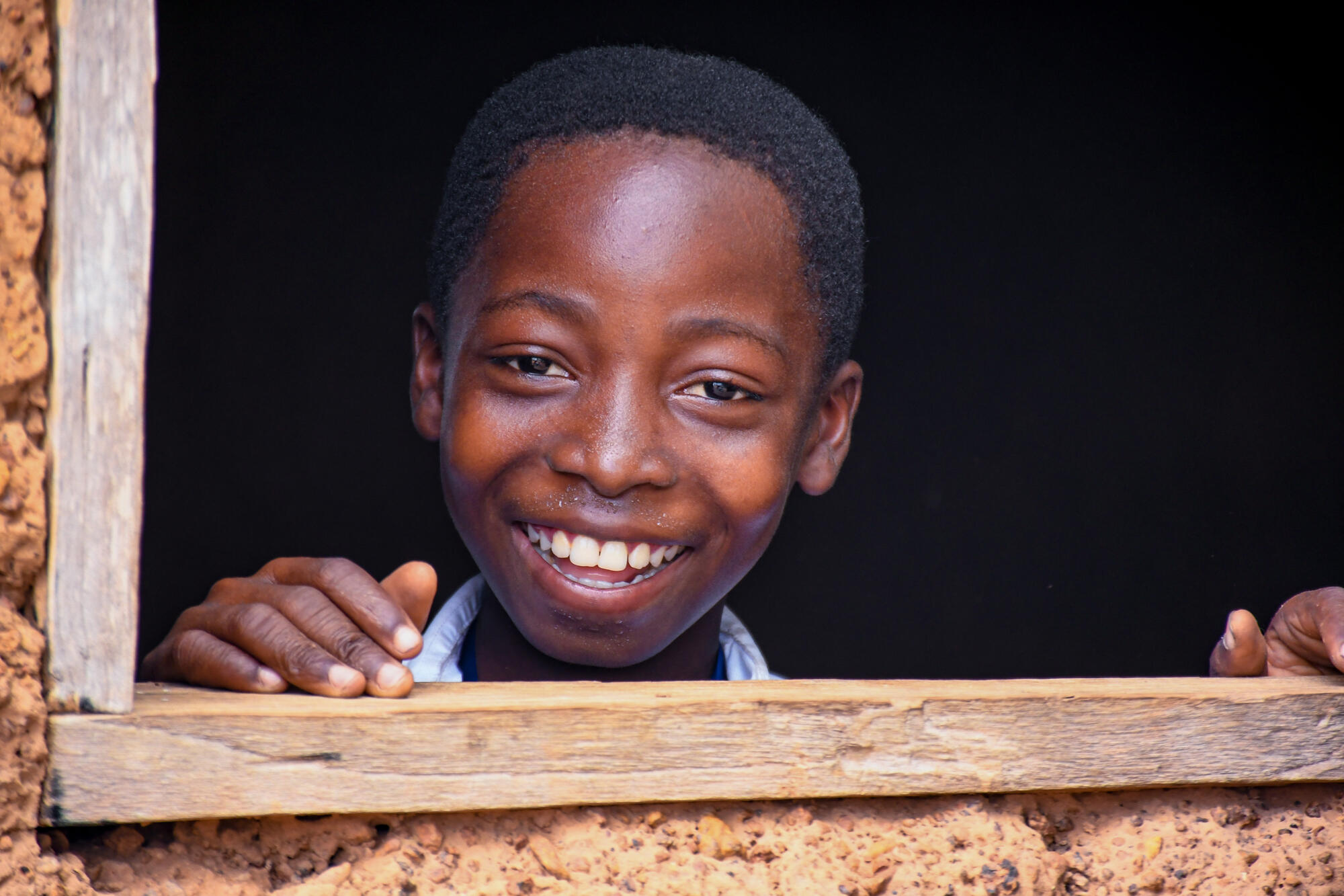 A boy smiling while looking through the window at school