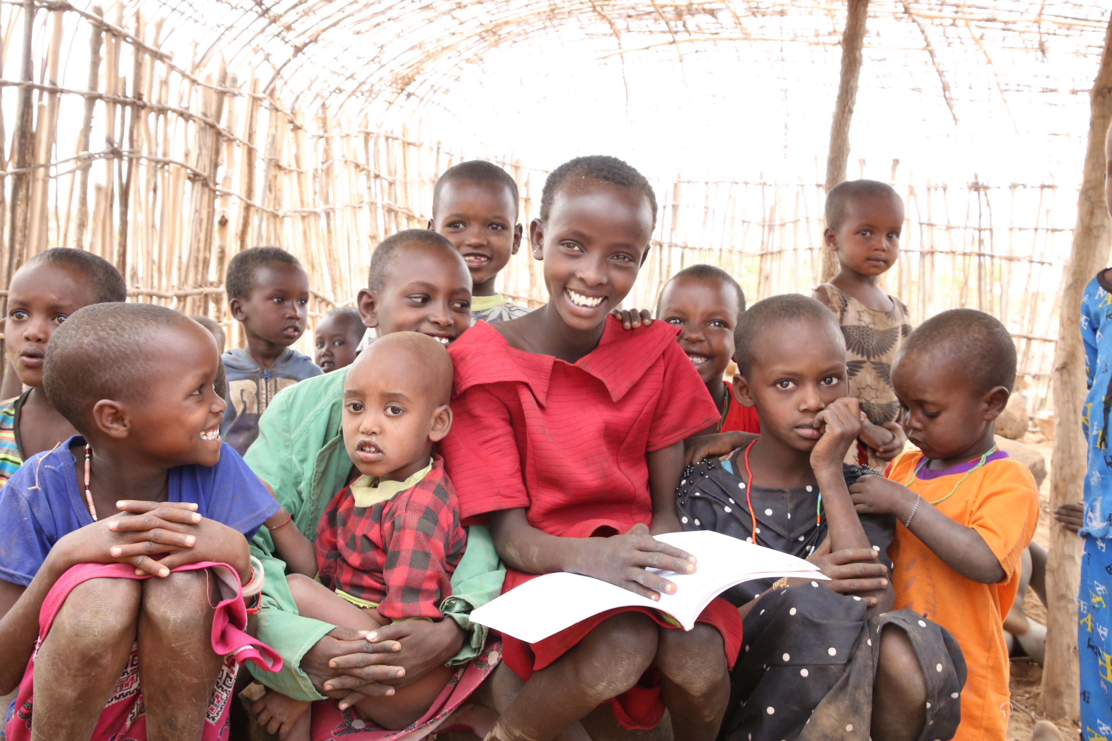 Children in Kenyan community gather to read a book