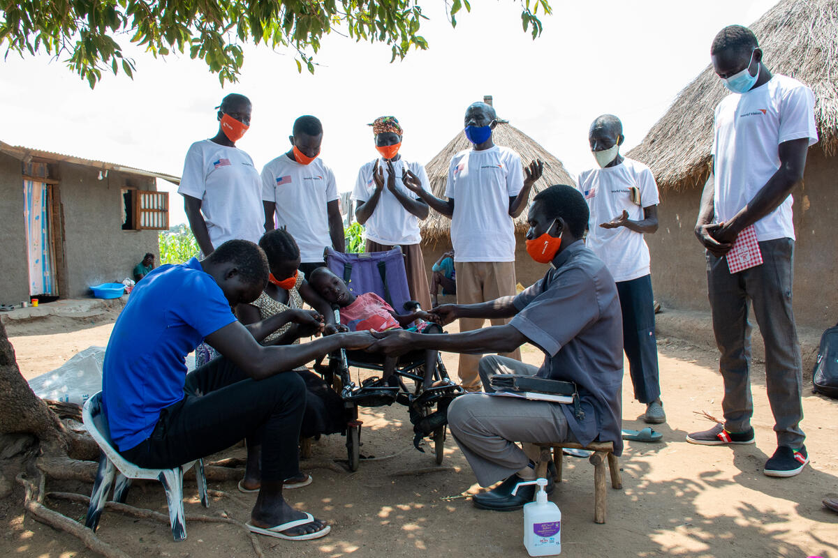 Pastor Willison Agele praying for Emmanuel Gale, during child monitoring visit in Yanagani, Bidibidi refugee settlement.