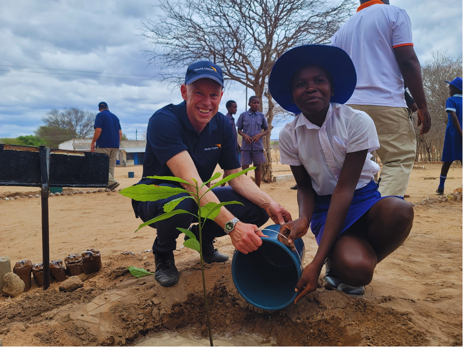 Andrew and a student from Dinde Primary School planting a tree