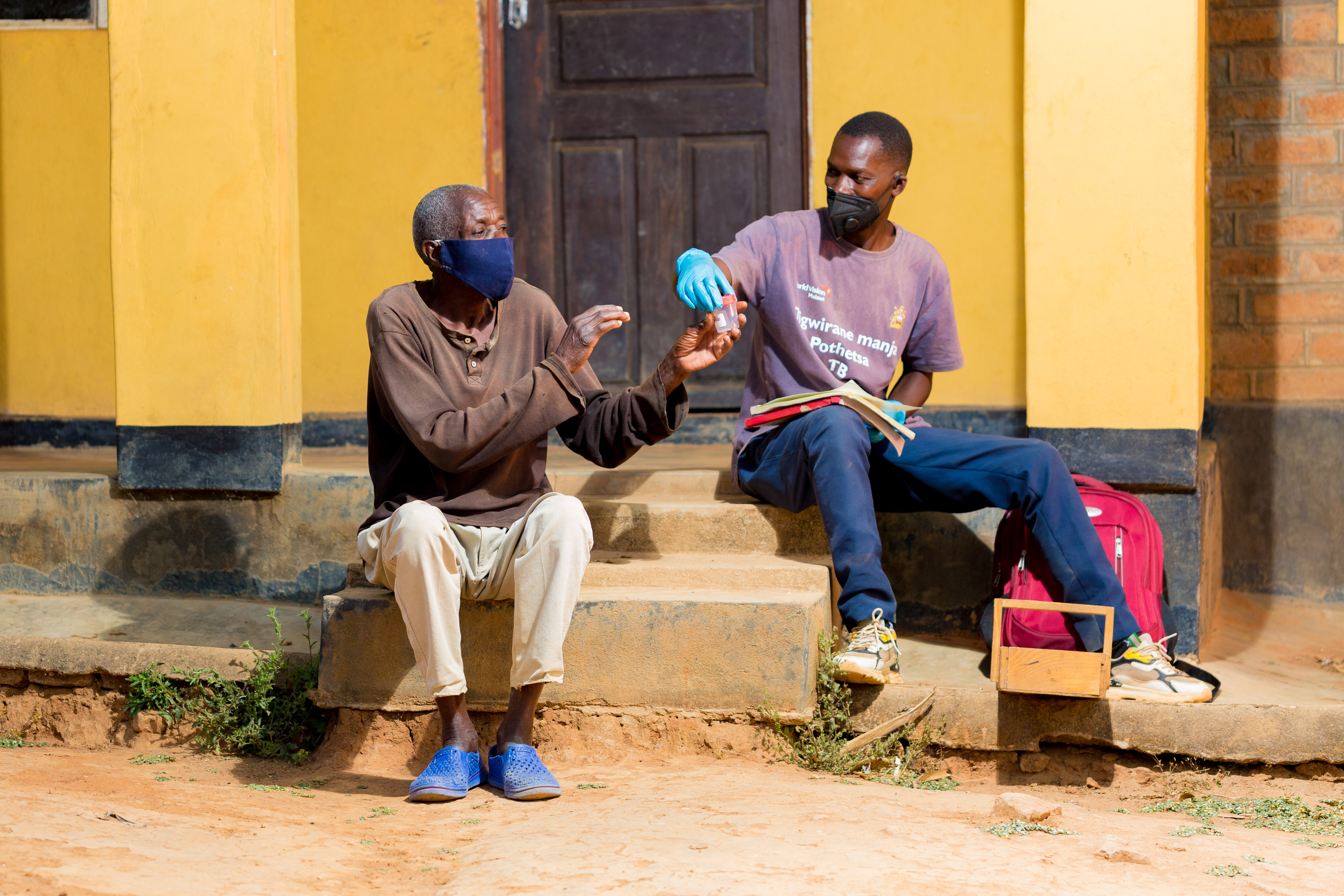 David Ngoma,TB Volunteer,Mzimba North in a dark blue trouser, attending to a client.