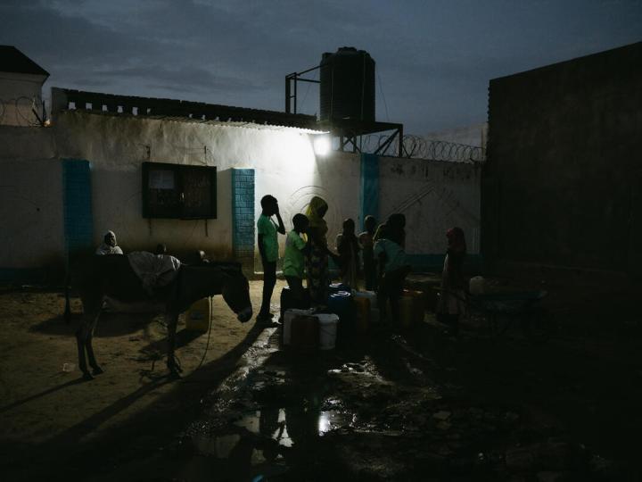 Children take turns filling jerrycans at a communal water point near a sprawling settlement camp in Adré, Chad.