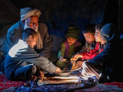 Afghan dad and kids sitting on a carpet