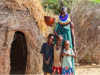 Awesit Lokele stands outside her makeshift shelter, known as a 'Manyatta,' with her three children by her side. She holds a traditional water drinking bowl, an item commonly used in her community. The simple yet powerful scene reflects the daily life of Awesit and her family. © World Vision Photo/Felix Pilipili