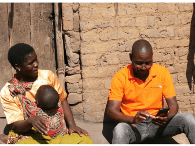 WV staff member with mother and child, recording digital data