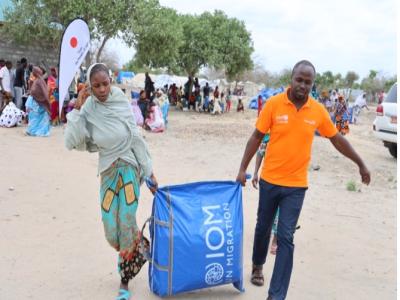 World Vision Kenya’s Dominic Maritim assists a community member in carrying the NFI bag she received during the distribution activity in Tana Delta Sub-County. © World Vision Photo/Jared Ontobo