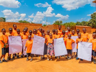 Alicia and children posing and showing messages at the World Children's Day celebration