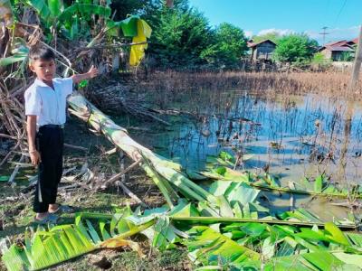 Child points at the damage caused by flooding in Laos