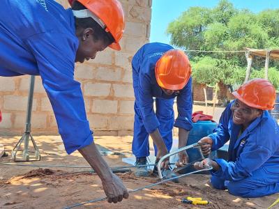 Women cutting iron to build a latrine