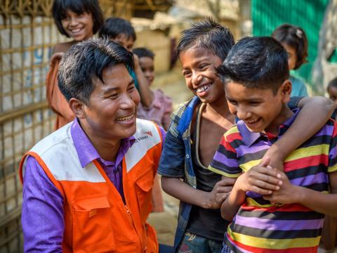 A World Vision employee smiles with some children in Bangladesh