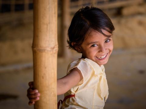 A girl in Bangladesh smiles in her home