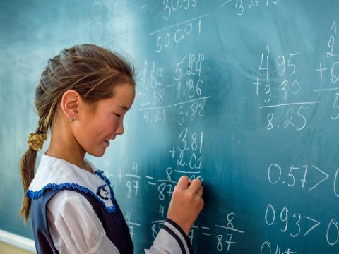 A girl in Mongolia writes on a chalkboard at school