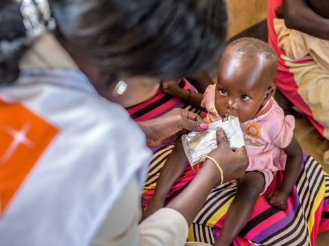 A baby receives a food pouch from a World Vision worker in Africa