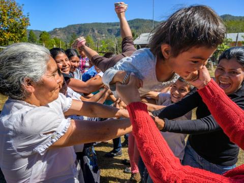 Child plays with their parents and community members