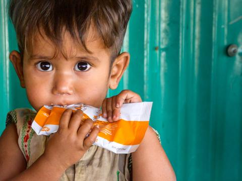 A boy eats food from a pouch in Rohyinga. 