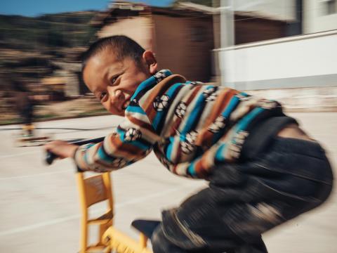 A child in Asia rides a scooter