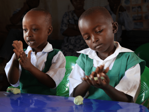 Children enjoy playing with modelling clay that comes with the School-in-a- Box Kit. © World Vision Photo/Hellen Owuor