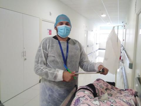 Doctor in protective gear stands in a hallway next to patient.