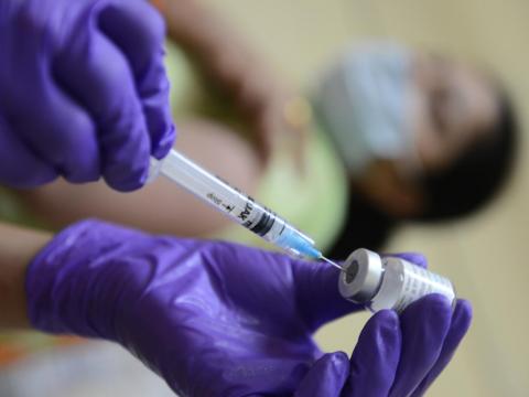 Vaccine being administered by a health professional wearing purple gloves