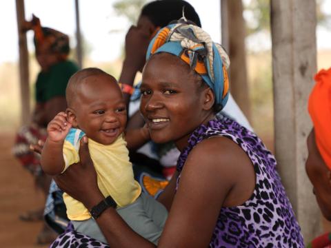 A woman jovially smiles with her child when they attended clinic at Iglansoni health center in Singida region